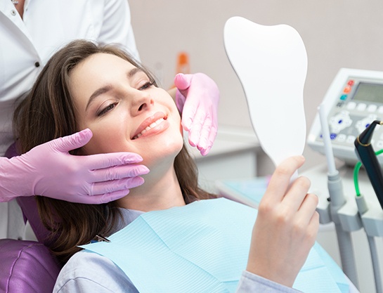 Cosmetic dental patient looking at her teeth in mirror