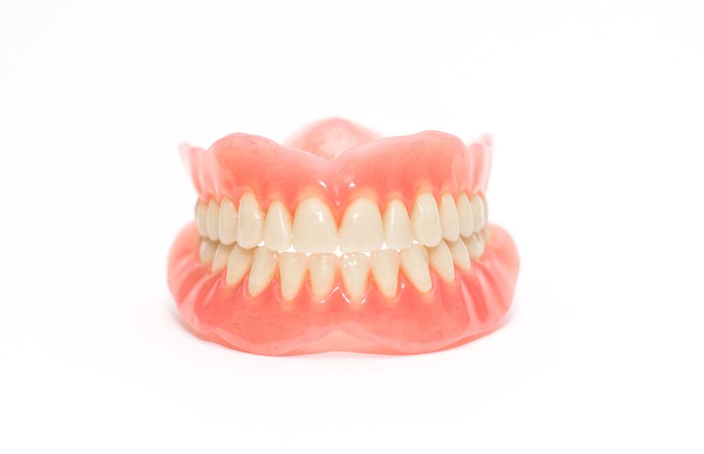 Full set of dentures glistening with a white background